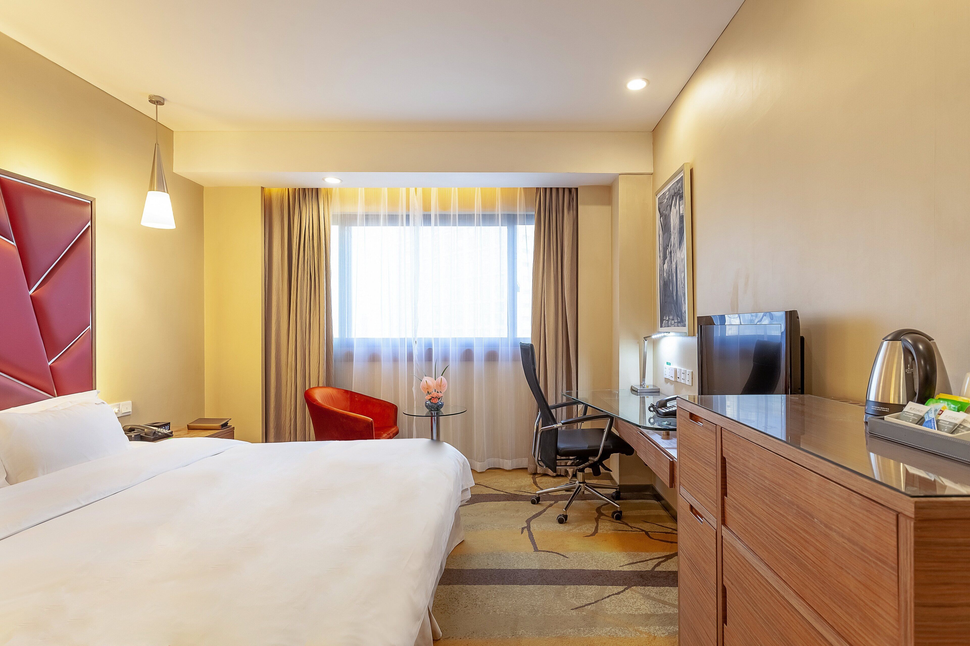 A hotel room with a bed, a desk, a chair, a television, and a coffee maker.