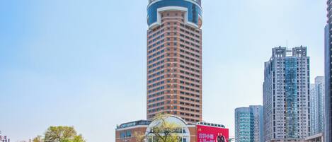 Un hotel alto con un letrero llamativo en la parte superior, rodeado de modernos edificios de gran altura.