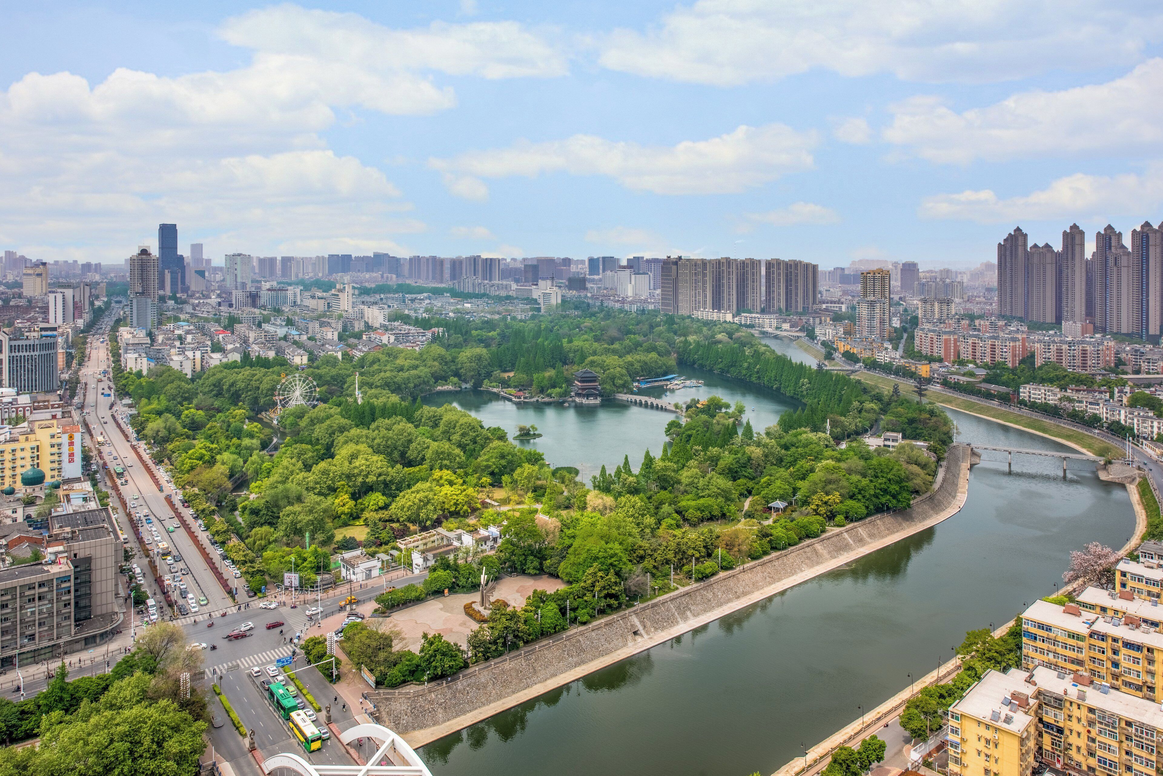 Un río atraviesa una ciudad con abundante vegetación y edificios a ambos lados.