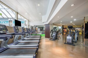 Un gimnasio con cintas de correr, bicicletas estáticas y máquinas de pesas.