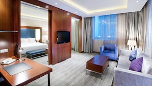 Une chambre d’hôtel comprenant un lit, une télévision, un bureau avec un téléphone, une chaise, un canapé et une table basse.