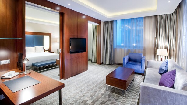 A hotel room with a bed, a TV, a desk with a phone, a chair, a sofa, and a coffee table. - Holiday Inn Shanghai Pudong by IHG (Shanghai)
