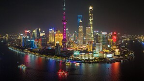 A nighttime cityscape with illuminated skyscrapers and a river. - Holiday Inn Shanghai Pudong by IHG (Shanghai)