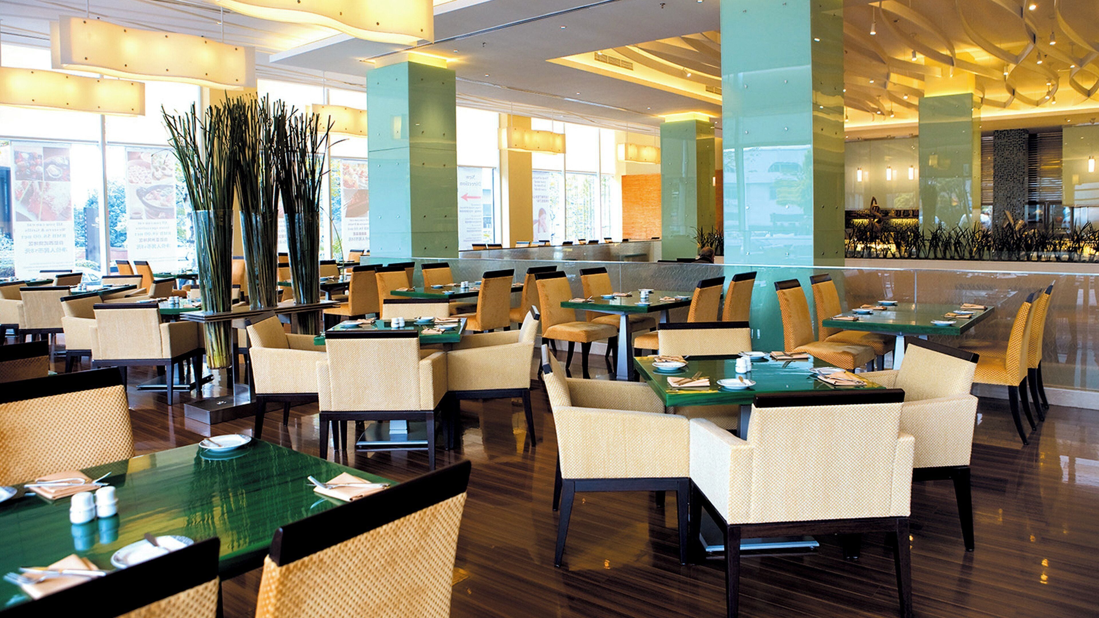 A spacious restaurant with multiple tables and chairs, large windows, and a modern interior design.