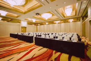 A conference room with rows of tables, chairs, and a carpeted floor.