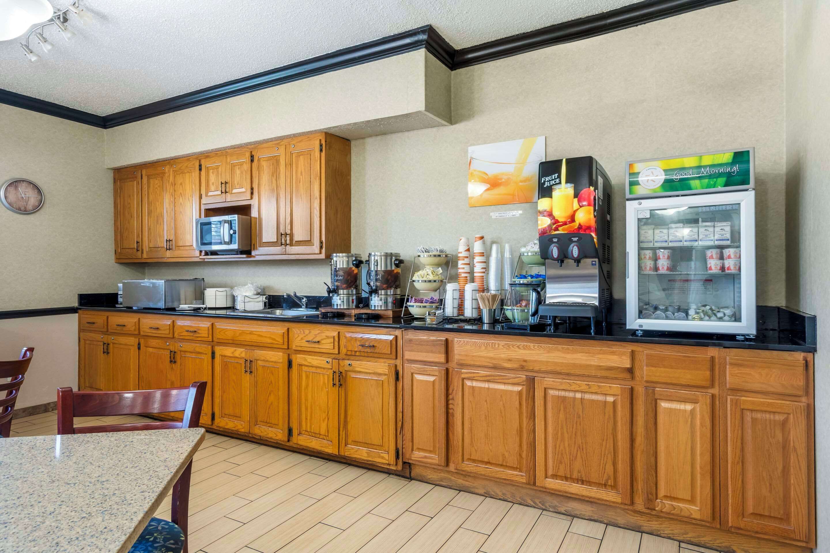 A kitchen with wooden cabinets, a microwave, coffee maker, and a refrigerator.