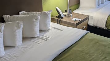 Quarto de hotel com uma cama grande, uma mesa de cabeceira com abajur e um telefone.