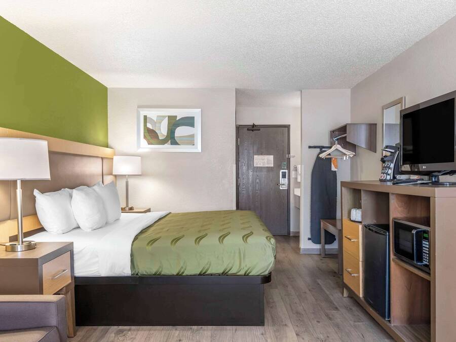 A hotel room with a bed, bedside tables, a TV, a microwave, and a wardrobe.