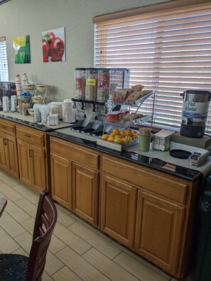 A breakfast bar with various food and drink dispensers, including cereal, coffee, and hot water.