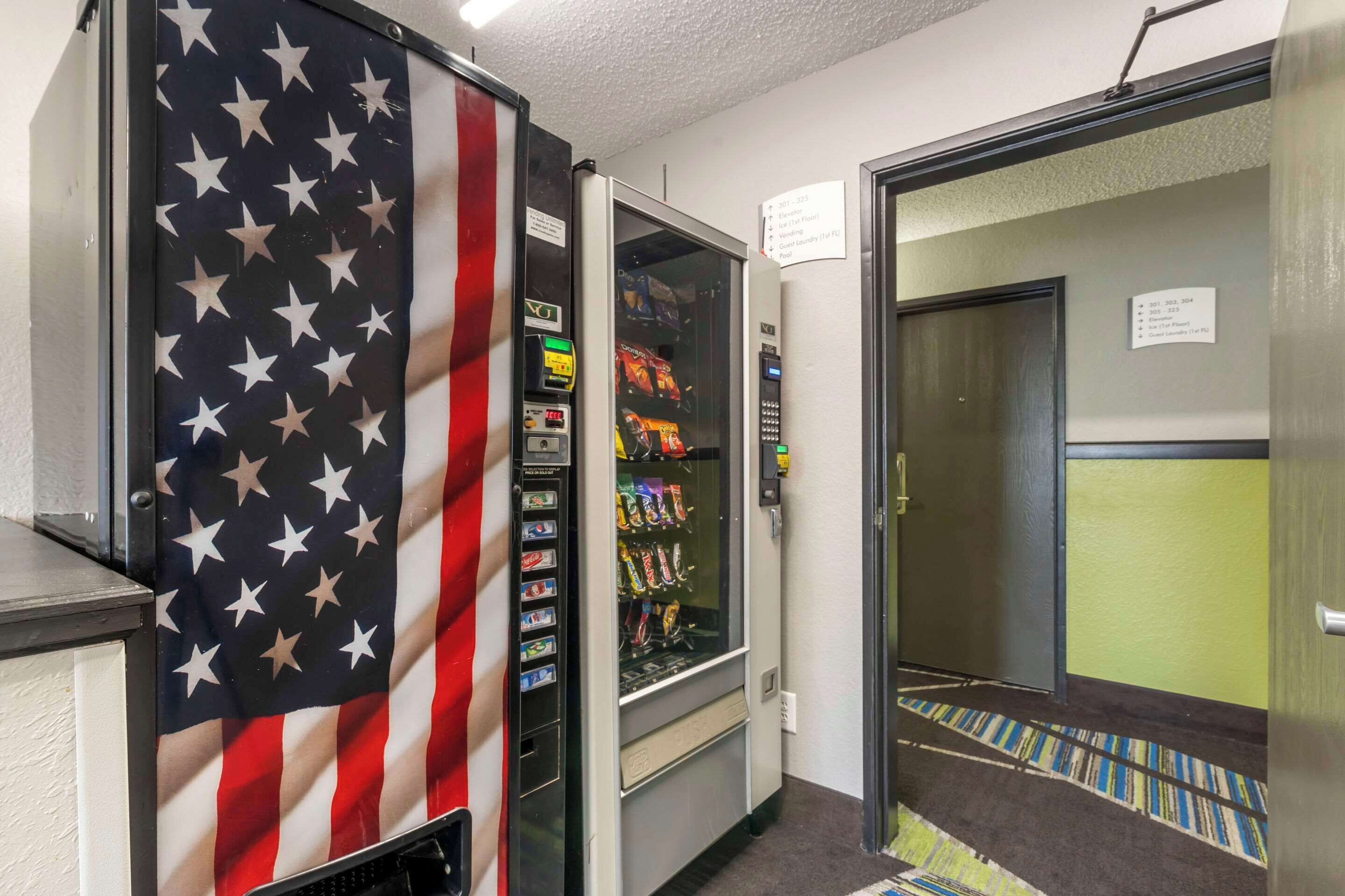 A hallway with a vending machine and a door leading to another room.