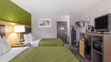 Habitación de hotel con dos camas, un escritorio con lámpara, televisor, microondas y refrigerador.