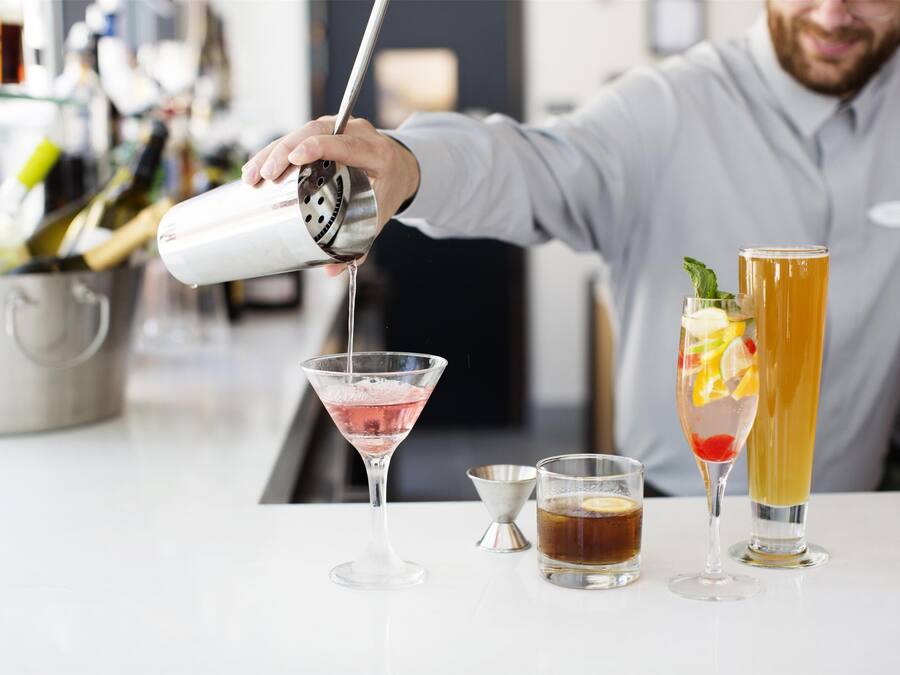 A bartender pouring a drink into a martini glass.