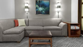 A modern living room with a grey sectional sofa, a wooden bench, and two wall-mounted floor lamps.