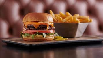 A burger with fries on a wooden board.