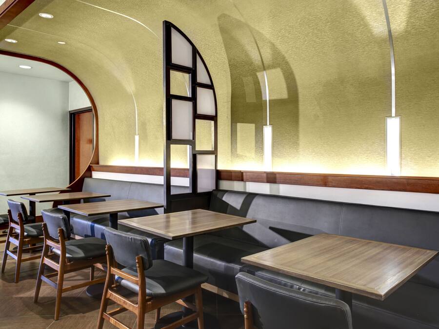 En restaurantindretning med båse, træborde og et buet loft.