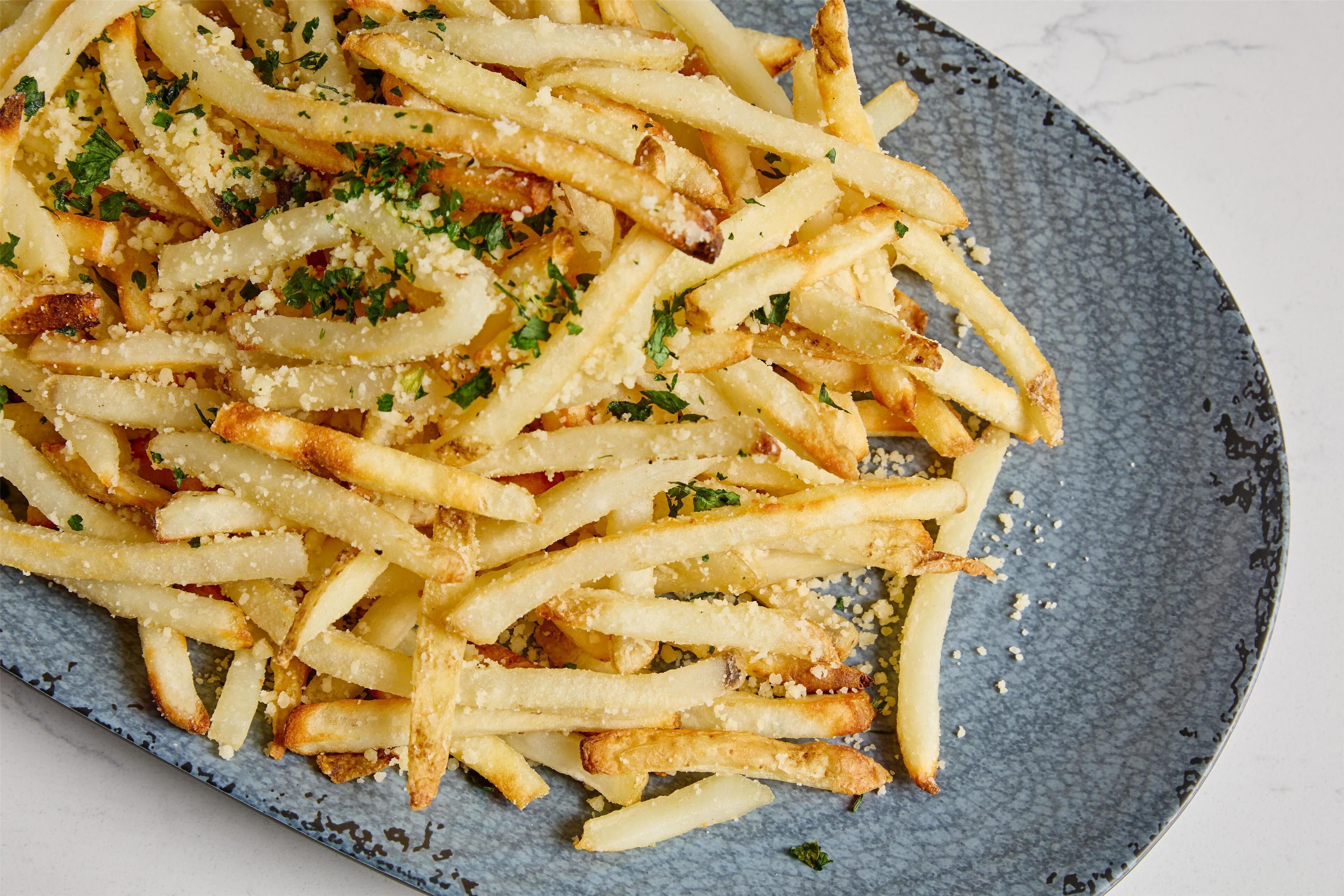 Ein Teller Pommes Frites mit Käse und Kräutern.