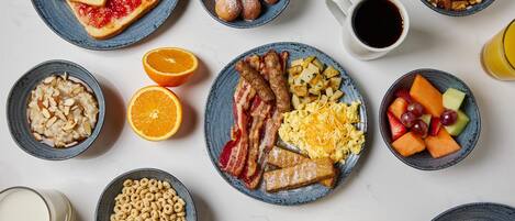 A breakfast spread with various dishes including toast, fruit, cereal, and eggs.