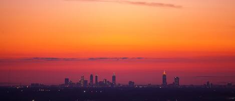 A city skyline at dusk with illuminated buildings against a gradient sky.