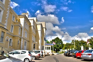 A hotel with a prominent sign, parked cars, and a clear blue sky with clouds. - Best Western London Queens Crystal Palace Hotel (London)