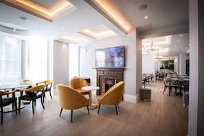 Een moderne hotel lobby met een open haard, een televisie en een eethoek.