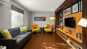 Una sala de estar moderna con un sofá, dos sillones amarillos, un televisor y una estantería.
