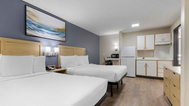 A hotel room with two beds, a kitchenette, and a painting on the wall. - Extended Stay America Suites Arlington (Arlington)