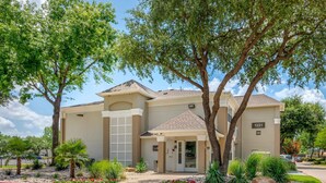 A two-story building with a beige facade, a garage, and a small entrance area with a door. - Extended Stay America Suites Arlington (Arlington)