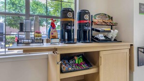 A coffee station with two coffee dispensers, a bottle of hand sanitizer, and a tray of snacks. - Extended Stay America Suites Arlington (Arlington)