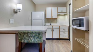 A compact kitchenette with a refrigerator, microwave, and wooden cabinets. - Extended Stay America Suites Arlington (Arlington)
