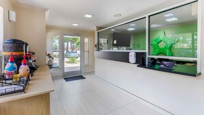 A reception area with a counter, a green decorative wall, and a door leading outside. - Extended Stay America Suites Arlington (Arlington)