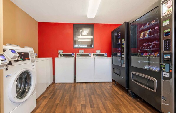 Una sala de lavandería con lavadoras, secadoras y una máquina expendedora.