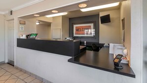 A reception desk with a 'WELCOME' sign, a digital kiosk, and a cash register.