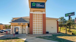 A Stay America Suites hotel with a prominent entrance, a lobby, and a parking area.