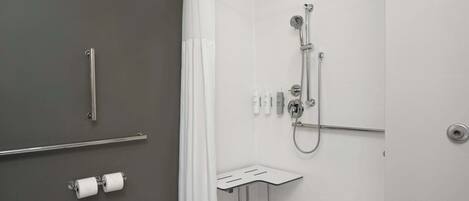 A modern bathroom with a shower, toilet, and grab bars.