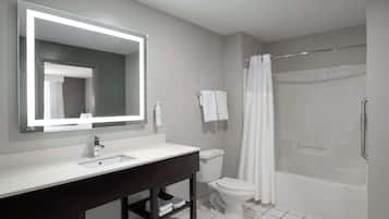 Un baño moderno con un espejo grande, un lavabo blanco y una ducha con puerta de cristal.