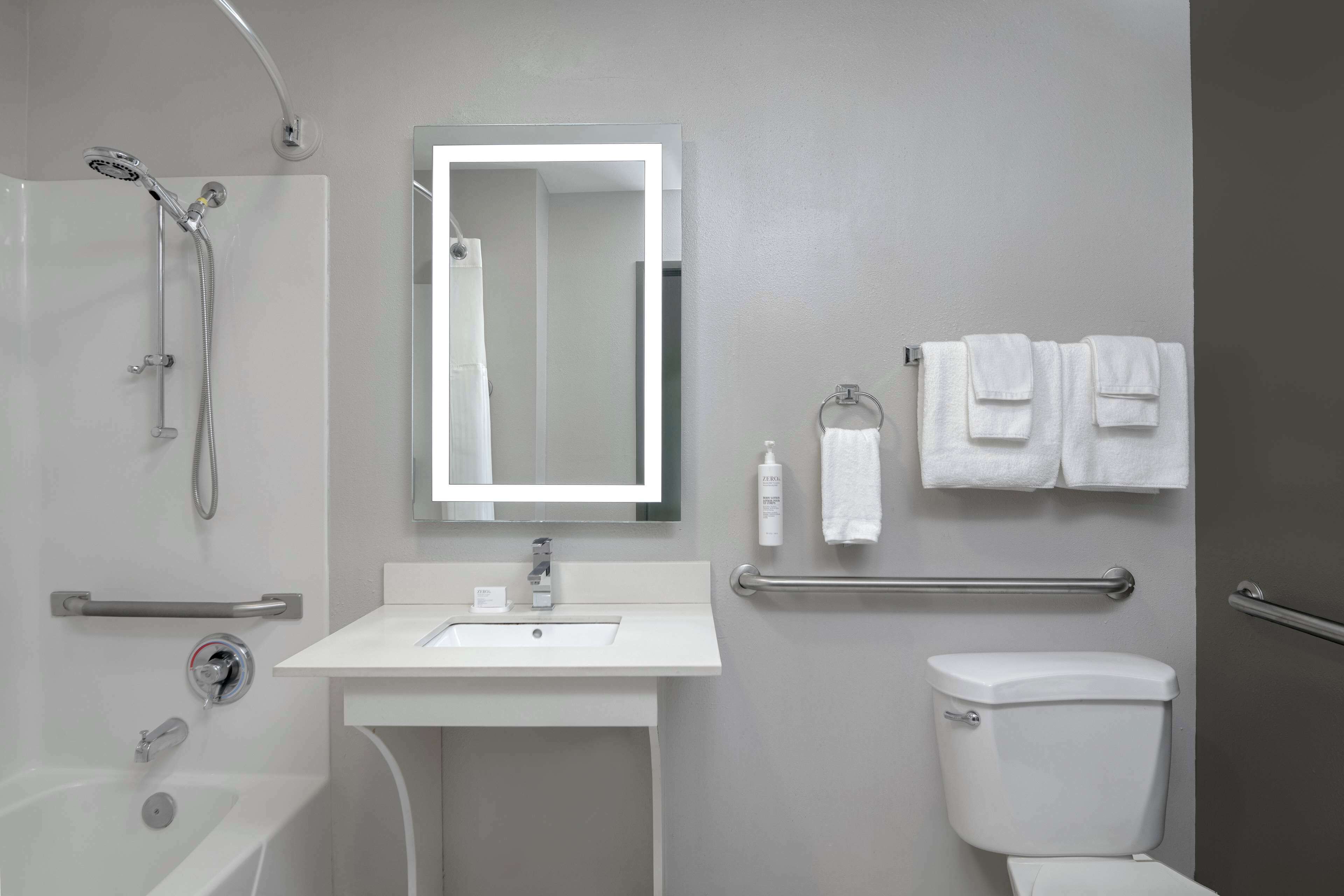 Une salle de bain moderne équipée d’une baignoire, d’un lavabo, de toilettes et d’une douche avec un pommeau de douche amovible.