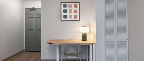 A small room with a desk, chair, and a framed picture on the wall.