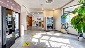 A clean, well-lit indoor area with a vending machine, a snack shop, and a large potted plant. - B&B HOTEL Orly Rungis Aéroport (Rungis)