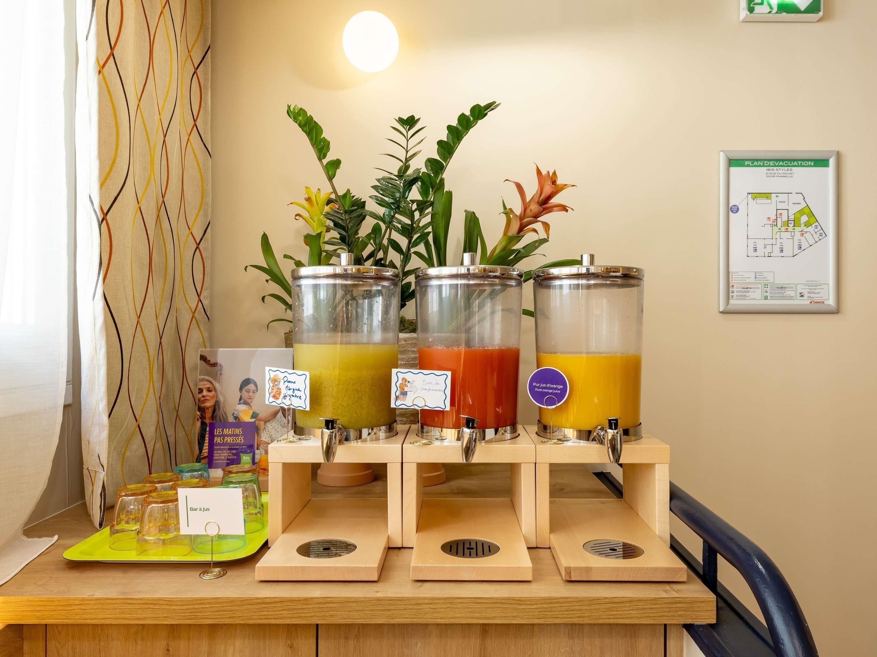 A juice bar with three dispensers, a map on the wall, and a plant in the background.
