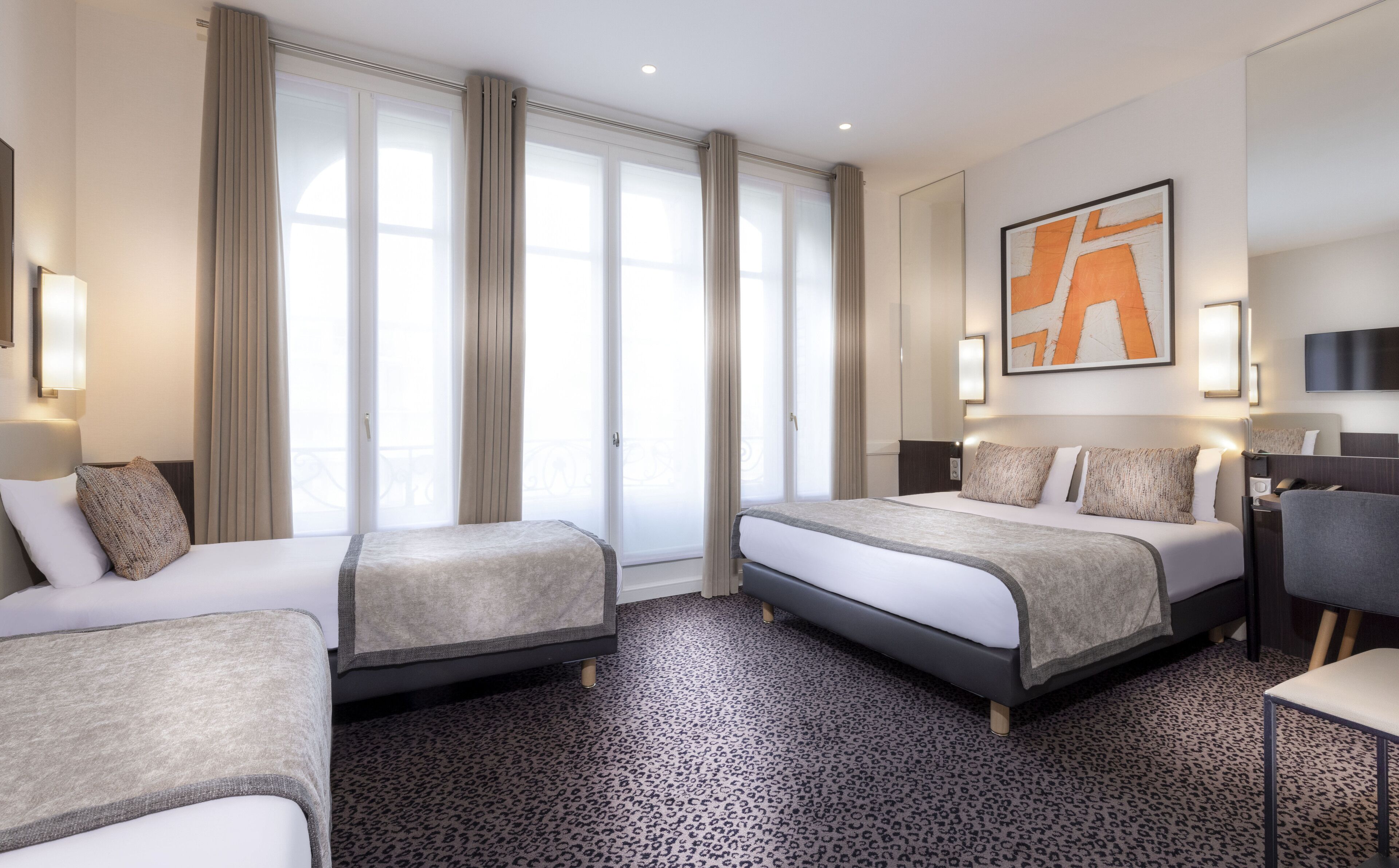 Ein Hotelzimmer mit zwei Betten, einem großen Fenster mit Vorhängen, einem leopardenmuster Teppich und einem modernen, abstrakten Gemälde an der Wand.