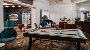 A billiards table in a well-lit room with modern furniture and a piano.