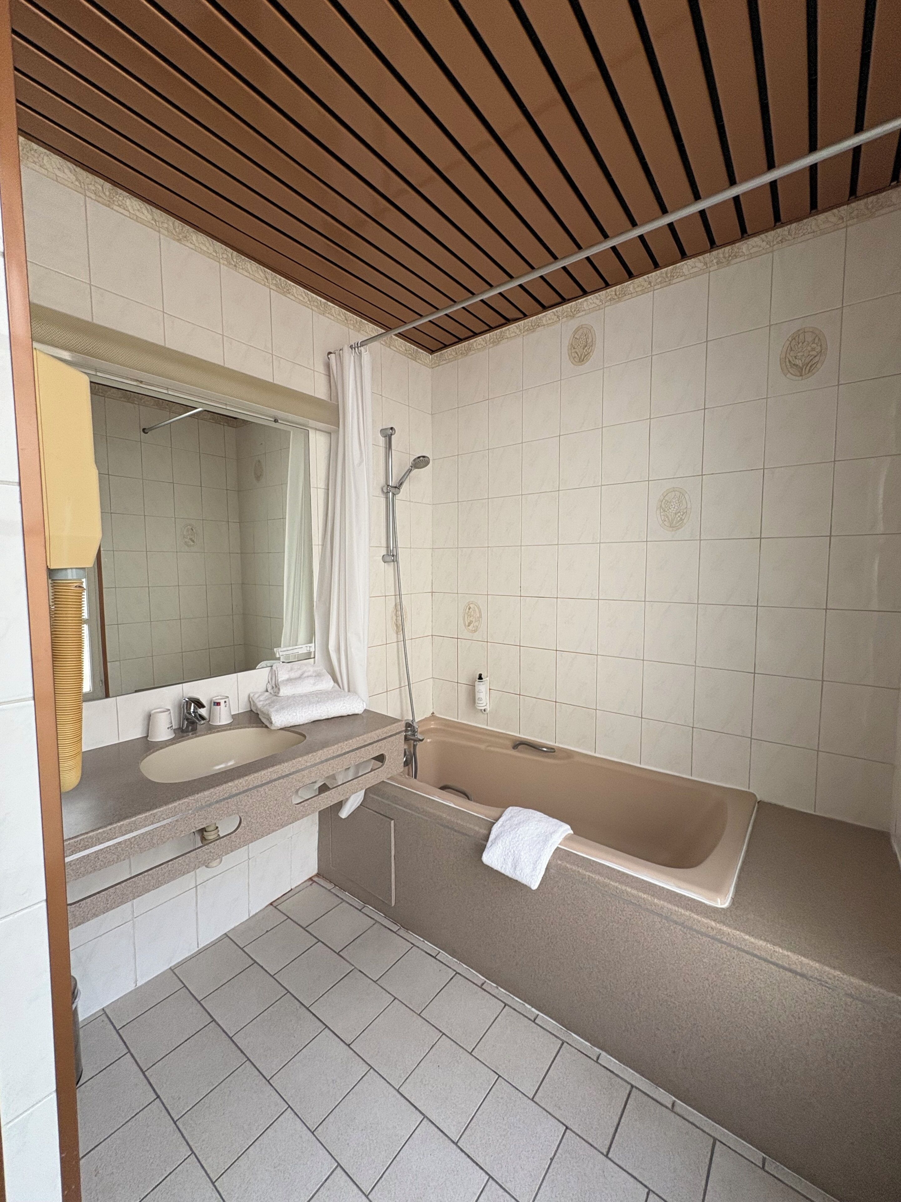 A bathroom with a bathtub, a sink, a mirror, and a shower.