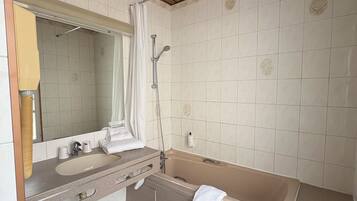 A bathroom with a bathtub, a sink, a mirror, and a shower.