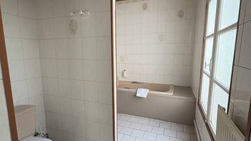 A bathroom with a toilet, a bathtub, and a shower area.