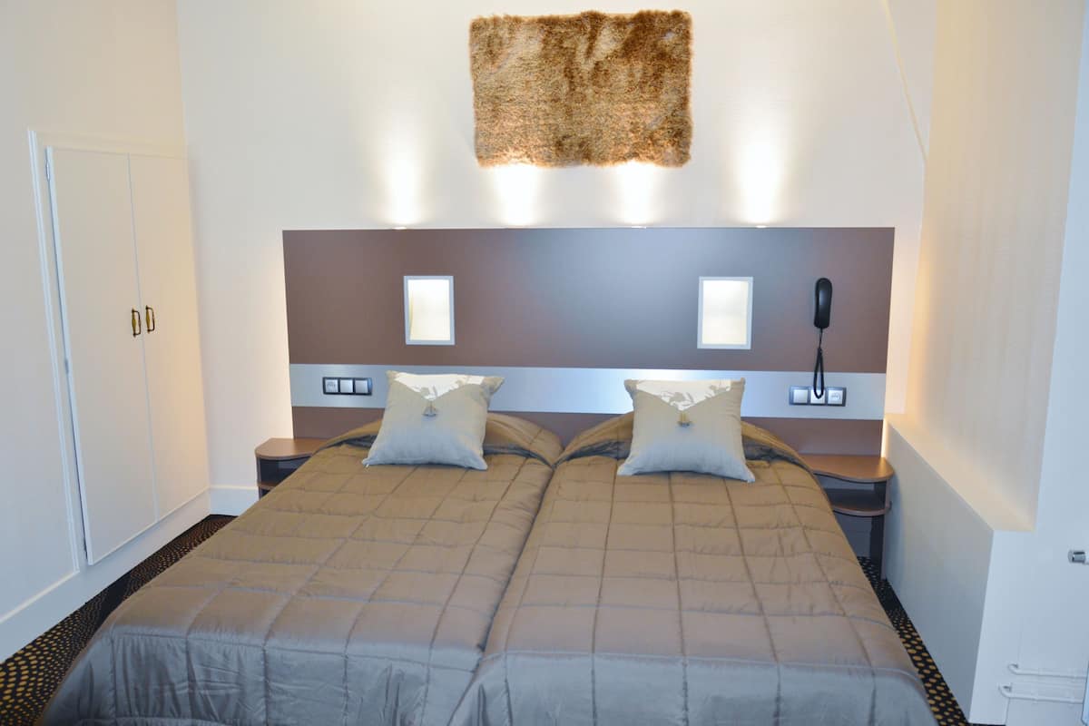A double bed with a headboard, two bedside tables, and a wall-mounted telephone.