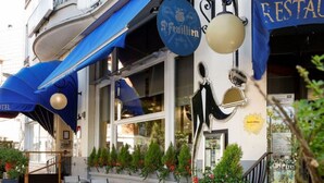 An outdoor seating area with tables and chairs, a blue awning, and a sign for 'Feuillien'.