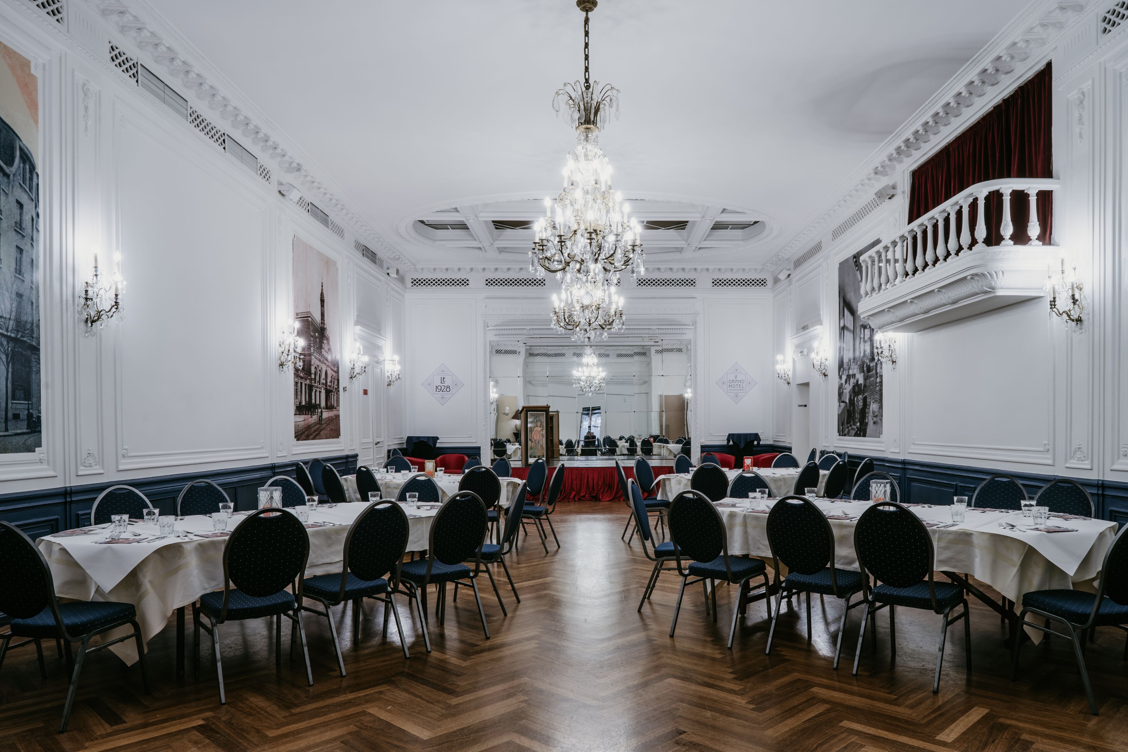 Uma sala de jantar formal com várias mesas, cadeiras e um lustre.