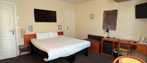 A hotel room with a bed, a desk, a chair, a television, and a small cabinet.