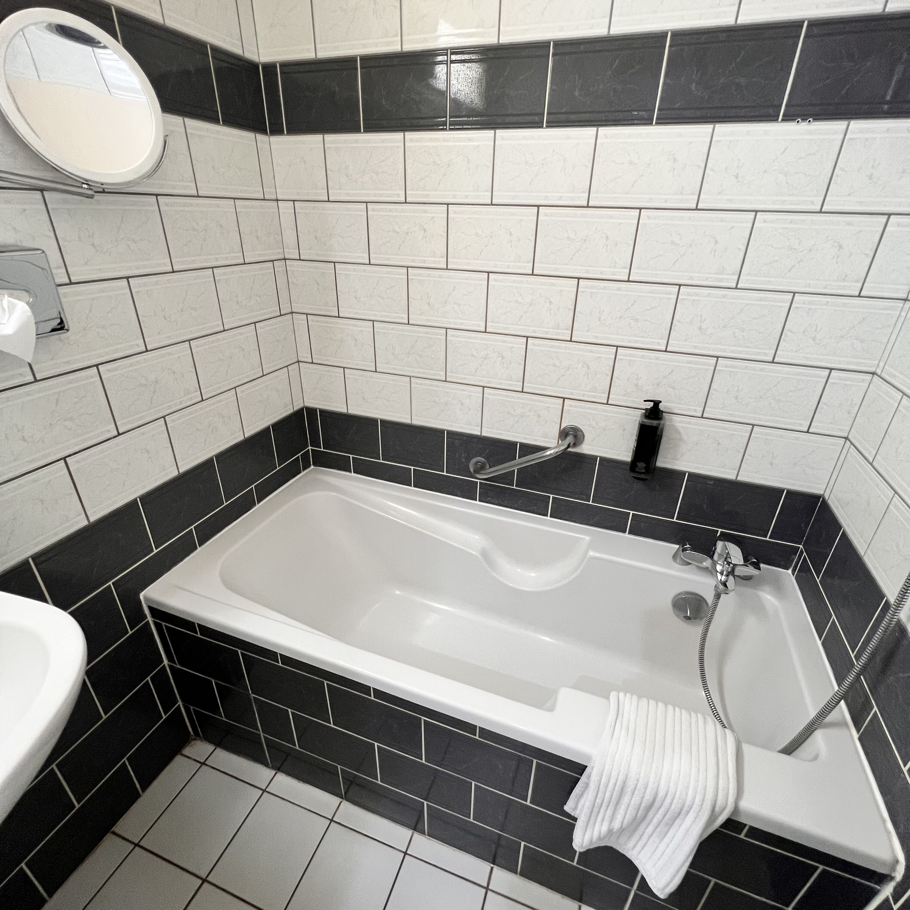 Een badkamer met een bad, een wastafel en een spiegel.
