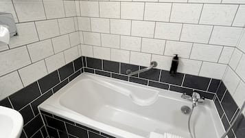 Een badkamer met een bad, een wastafel en een spiegel.